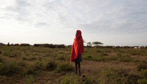 Marcy Mendelson, The Samburu Story | A Samburu boy warms himself by the light of the rising sun. Outside Kisima, Samburu County, Kenya. August 22, 2013.