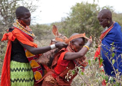 Marcy Mendelson, The Samburu Story | After hours of butchering the ritually slaughtered cows, the women pack and carry the meat in heavy sacks strapped across their head and balanced on their backs.  They return to the grand manyatta to prepare the feast.