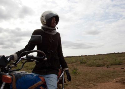 Marcy Mendelson, The Samburu Story | A dash of modernity as a young Samburu man runs errands to the village of Kisima for cell phone minutes and cigarettes during the Lmuget ceremony.  Outside Kisima, Samburu County, Kenya.  August 22, 2013.