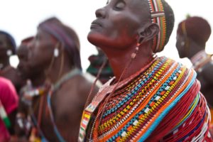 Marcy Mendelson, The Samburu Story | A Samburu mother dances alongside hundreds of moran, celebrating their graduation into elder warrior status of the Loimisi Samburu clan. Outside Kisima village, Samburu, Kenya.