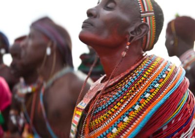 Marcy Mendelson, The Samburu Story | A Samburu mother dances alongside hundreds of moran, celebrating their graduation into elder warrior status of the Loimisi Samburu clan.  Outside Kisima village, Samburu, Kenya.