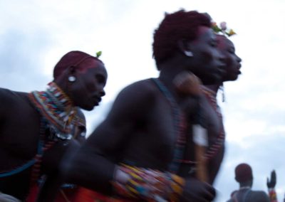 Marcy Mendelson, The Samburu Story | Samburu moran (warriors) celebrate their graduation into senior status with singing and dancing through the night.  Outside Kisima village, Samburu, Kenya.  August 22, 2013.